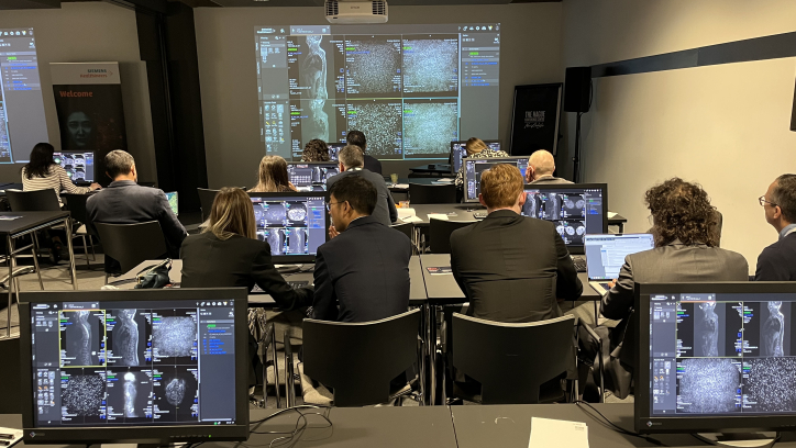 A group of people in a room with computers attending a presentation on medical imaging.