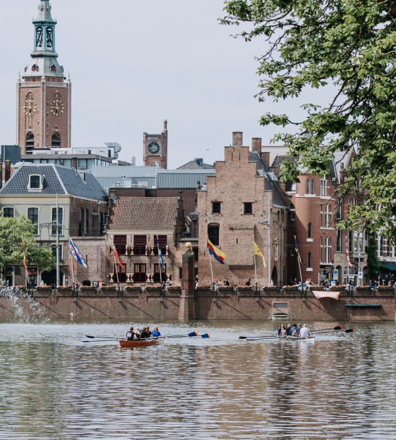 People rowing on the water with the Binnenhof in the background