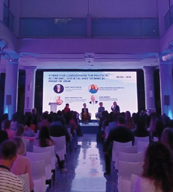 A panel discussion with a speaker and audience in a hall.