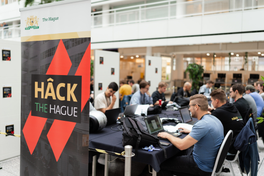 Image participants sitting behind laptop at the event Hack The Hague