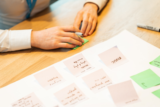 A hand is placing a sticky note on a table with more sticky notes
