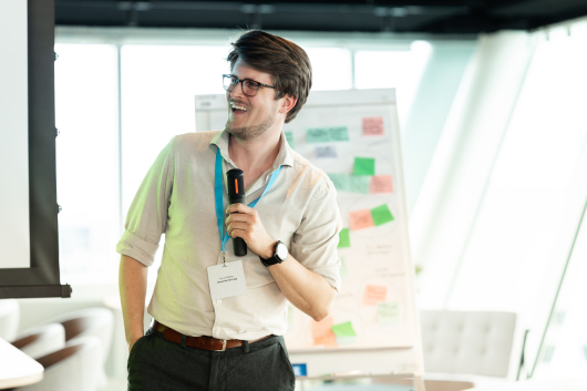 A man with a microphone is speaking enthusiastically to an audience.