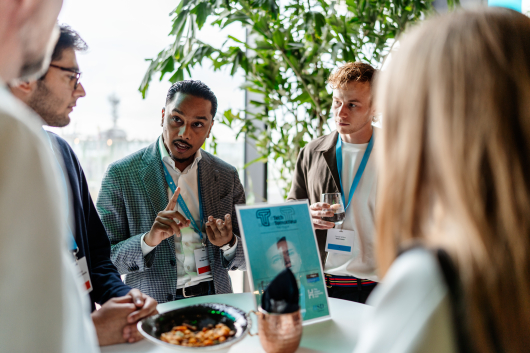 A group of people engaged in conversation at an event with food and drinks.