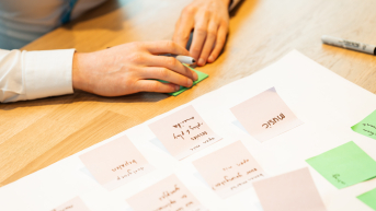 A hand is placing a sticky note on a table with more sticky notes