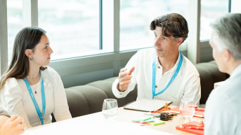 A man and woman conversing during a meeting.