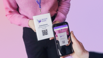 A person holds an event badge while a smartphone scans the QR code.
