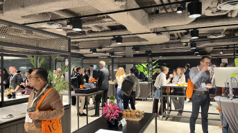 People in a modern space with food and plants at a networking event.