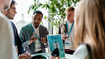 A group of people engaged in conversation at an event with food and drinks.