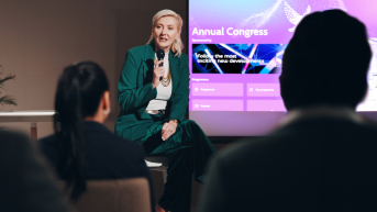 A female speaker presents during a conference.