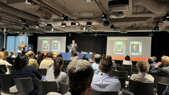 A speaker presents to an audience with images of Vermeer.