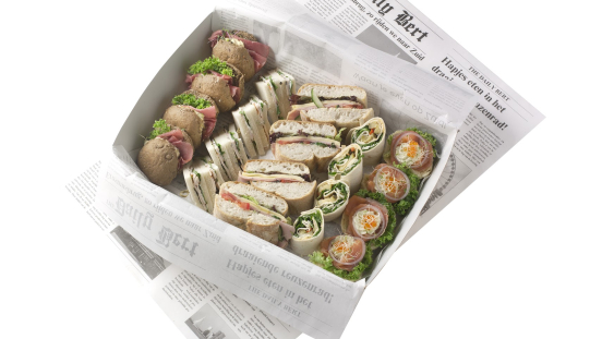 A box filled with assorted sandwiches and wraps on newspaper.