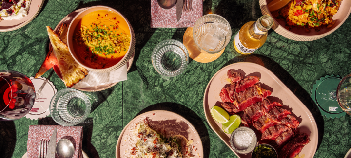Table setting with soup, meat, rice, and drinks.