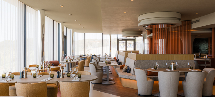 A stylish restaurant with round tables and comfortable chairs