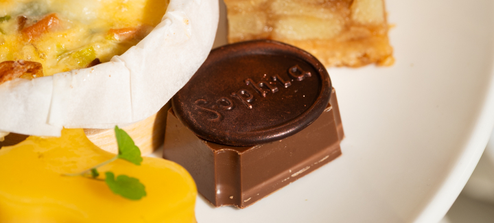 An assortment of small pastries, including a chocolate piece and a lemon tart.