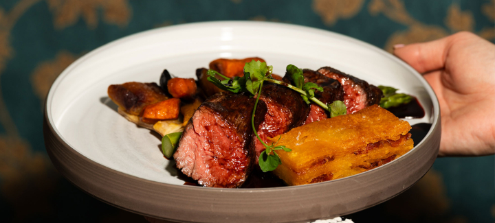 A plate with steak, grilled vegetables, and a glazed potato.