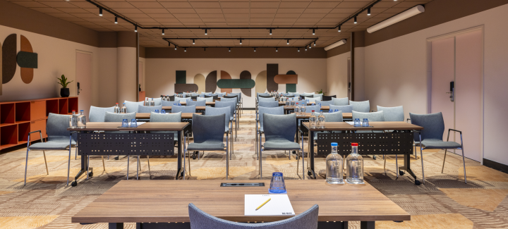 A modern meeting room with tables and chairs.