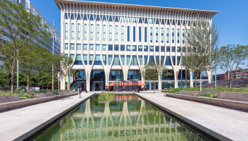 A modern building with a reflective water feature and trees in The Hague.