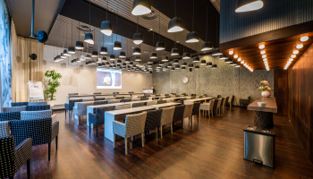 A stylish meeting room with tables and chairs, a projector, and a plant.