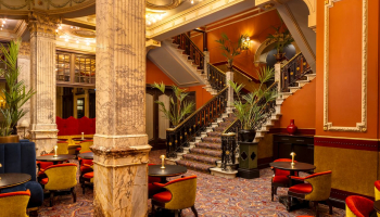 Stylish restaurant interior with marble columns and a staircase.