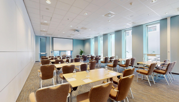 A modern meeting room with tables and chairs.