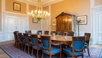 A meeting room featuring a large wooden table, chairs, and a chandelier.