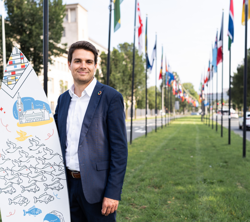Image of international sales advisor Joris holding branded surfboard of The Hague in the International Zone of The Hague