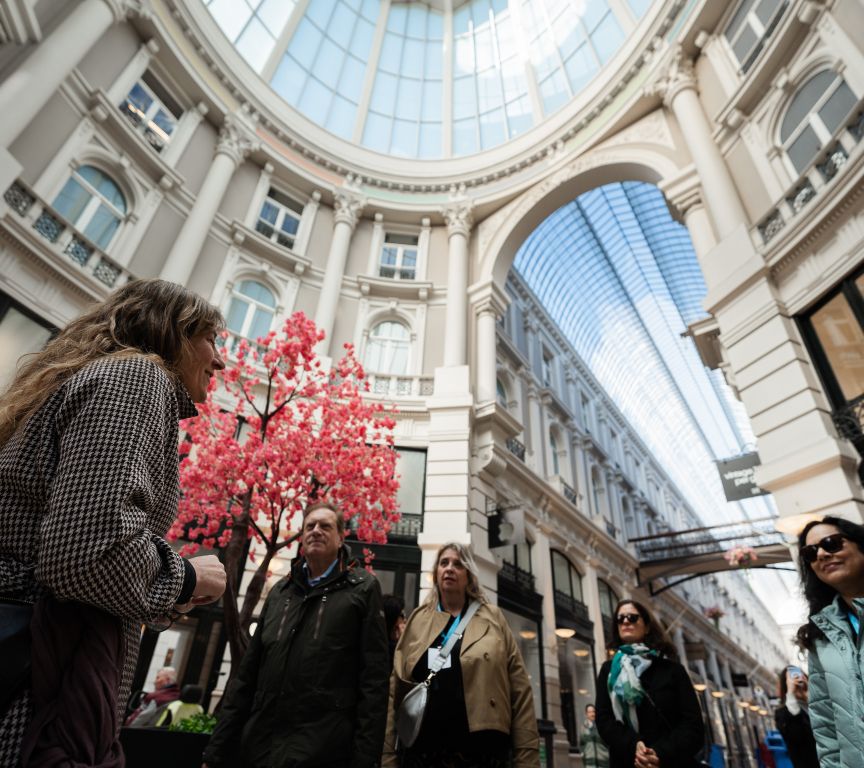 A group of people listening to a guide under a skylight.