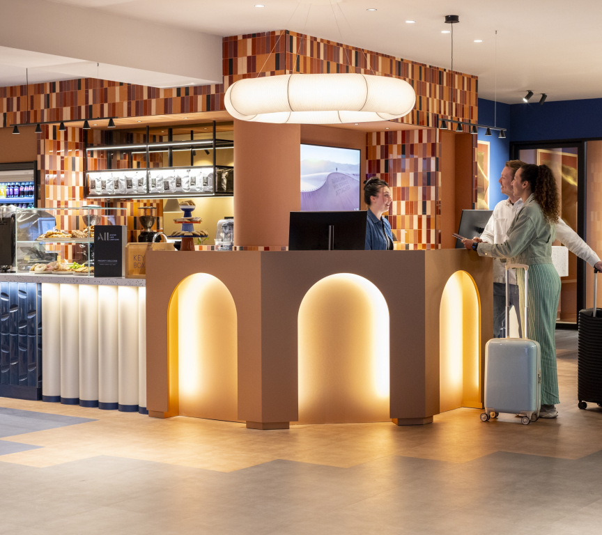 Two guests at the reception of a modern hotel with luggage.