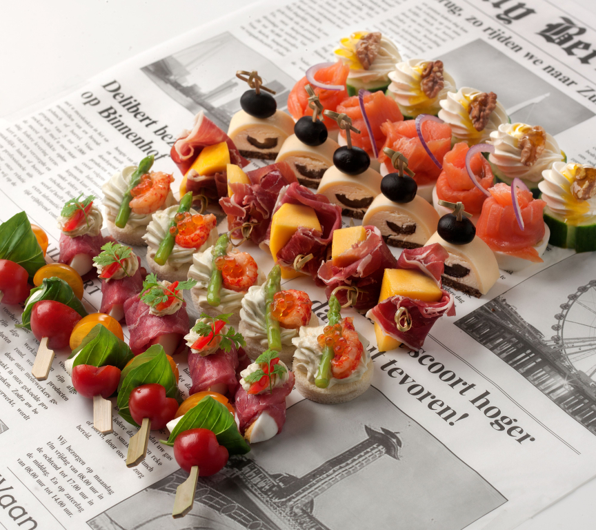 A platter with various appetizers on a newspaper