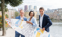 Image of three people of The Hague and Partners holding a branded surfboard standing in front of the Hofvijver in The Hague