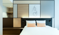 A modern hotel room featuring a large bed and artwork above the headboard.