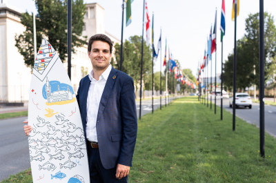 Image of international sales advisor Joris holding branded surfboard of The Hague in the International Zone of The Hague