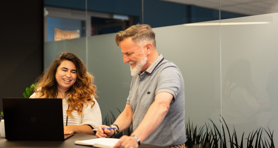 Two people are laughing while working together.