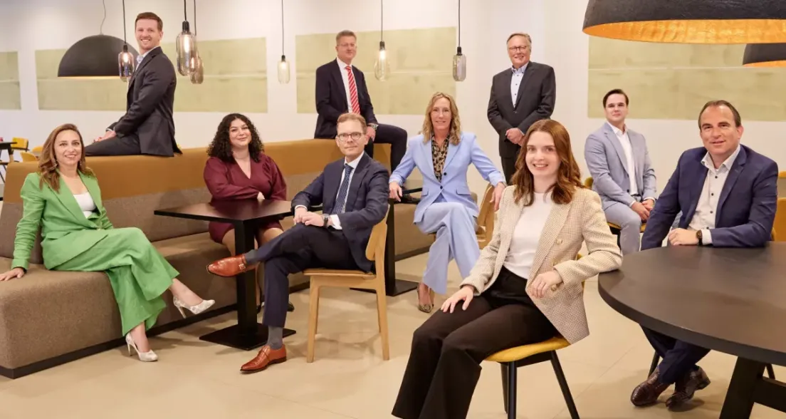 Ten professionals pose in a modern office space.