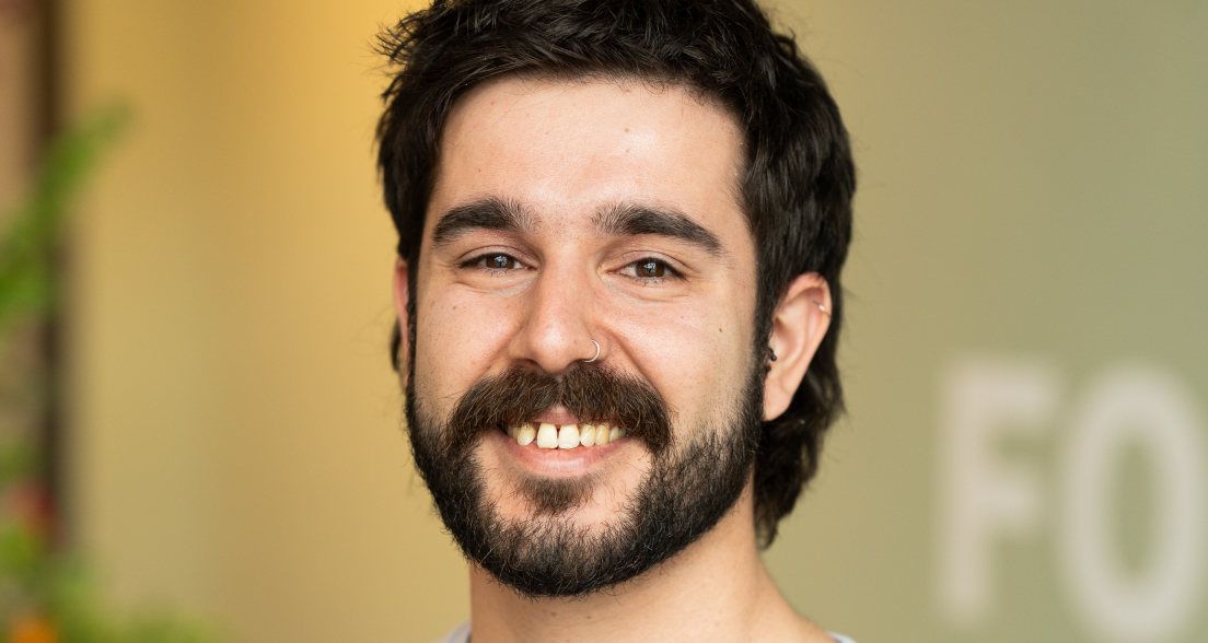 Young man with a beard wearing a light blue t-shirt saying 'The Hague Energized'.