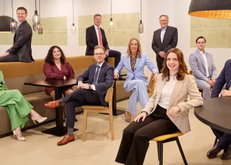 Ten business professionals sit and stand in a modern space.