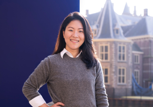 Woman in a gray sweater poses by the Binnenhof