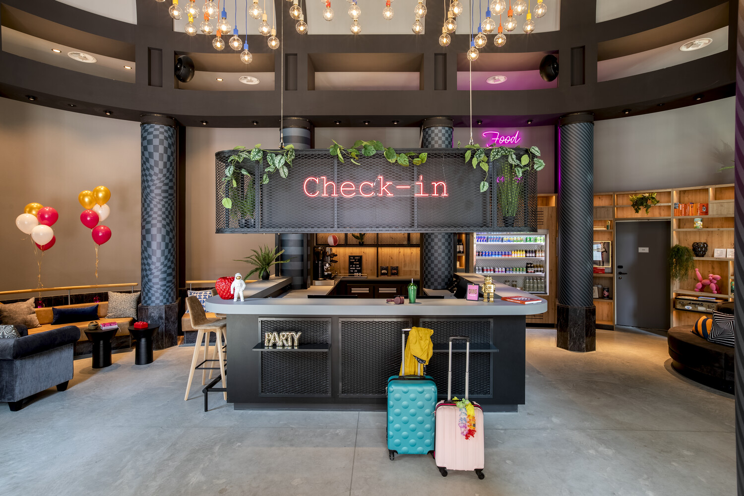 A modern check-in desk with colorful balloons and luggage.