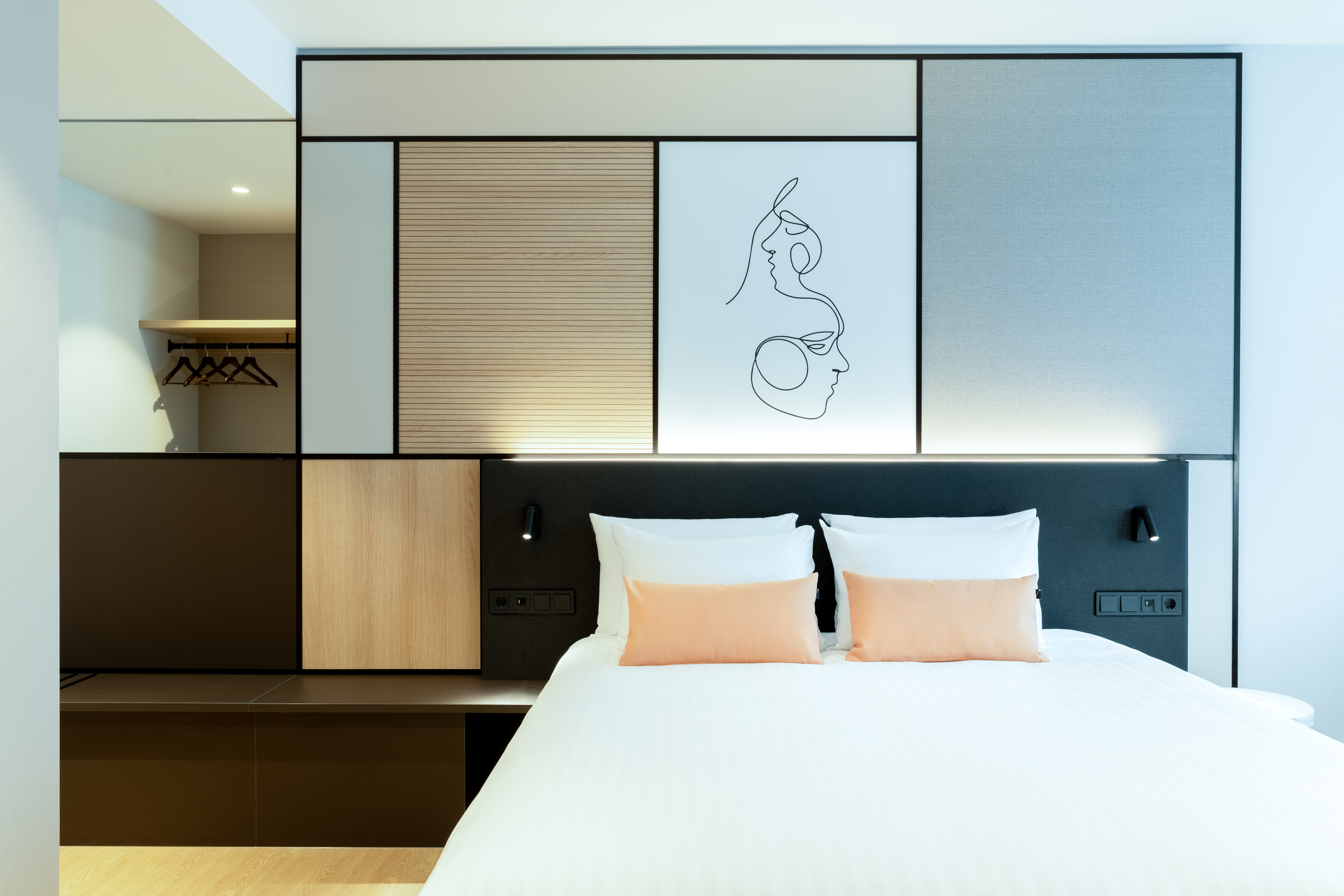 A modern hotel room featuring a large bed and artwork above the headboard.