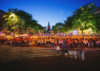 Crowded terraces with people under ambient lighting in the city.