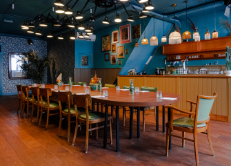 Spacious dining room with a long table, green chairs, and decorative lamps.