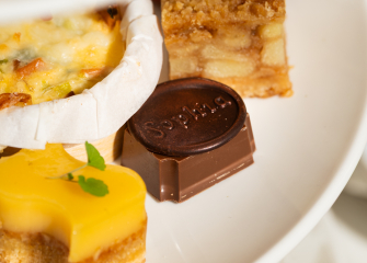 An assortment of small pastries, including a chocolate piece and a lemon tart.