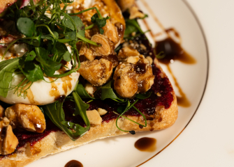 Sandwich with salad, nuts, and white cheese on a plate