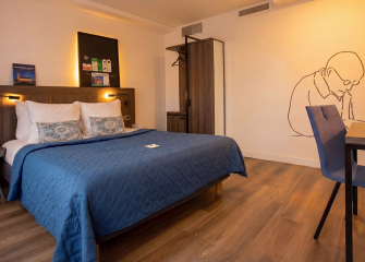 Stylish hotel room with a blue bed and wall art
