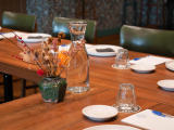 A table featuring a vase of flowers and glasses.