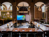 A meeting room with wooden tables, chairs, and a projector.