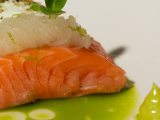 A slice of salmon with white sauce and green puree