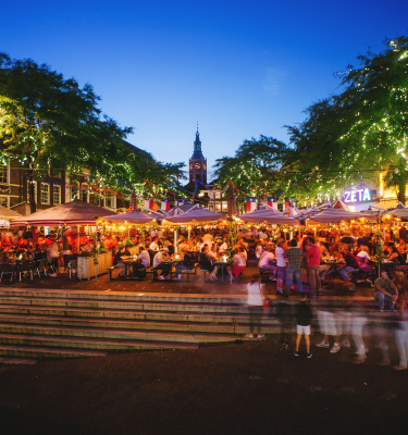Crowded terraces with people under ambient lighting in the city.