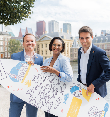 Image of three people of The Hague and Partners holding a branded surfboard standing in front of the Hofvijver in The Hague