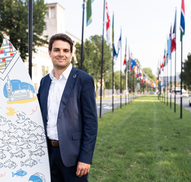 Image of international sales advisor Joris holding branded surfboard of The Hague in the International Zone of The Hague